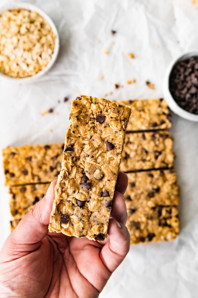 A handing holding up a rectangular peanut butter protein bar.