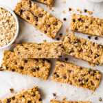 Rectangular peanut butter protein bars spread across a sheet of parchment paper.