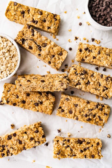 Rectangular peanut butter protein bars spread across a sheet of parchment paper.