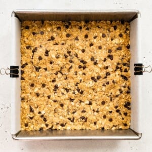 Peanut butter protein bar mixture in a square baking pan lined with parchment paper.