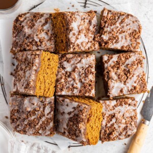 Nine pumpkin coffee cake squares on a sheet of parchment paper.