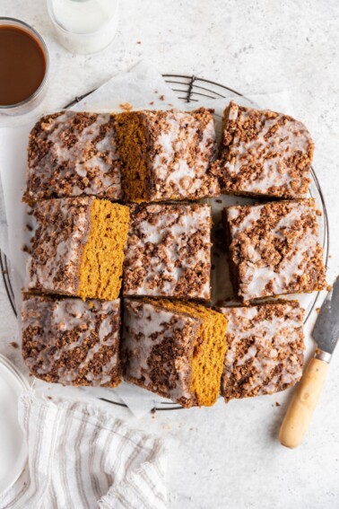 Nine pumpkin coffee cake squares on a sheet of parchment paper.