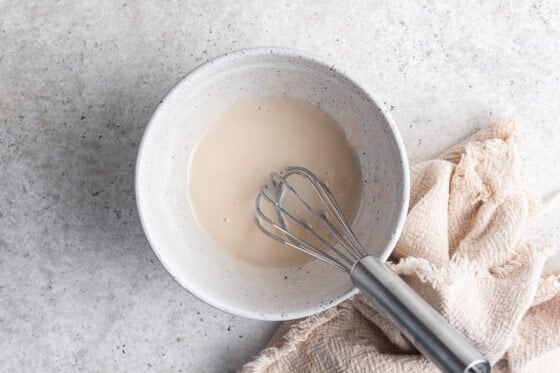 Icing mixture in bowl with a whisk.