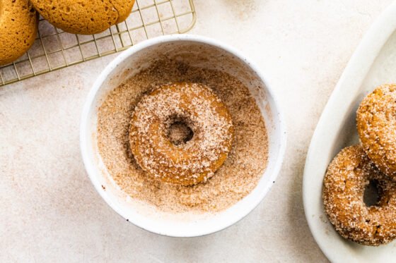 Coating donuts in cinnamon sugar mixture.