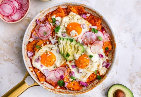 Eggs cooked in red chilaquiles topped with cotija cheese, avocado and radishes.
