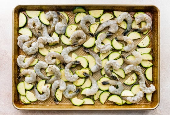 Zucchini, shrimp and spices tossed together on a sheet pan.