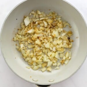 Sautéing onion and garlic in a sauté pan.