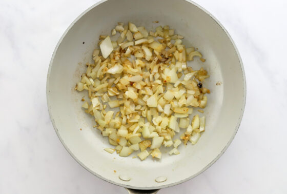 Sautéing onion and garlic in a sauté pan.