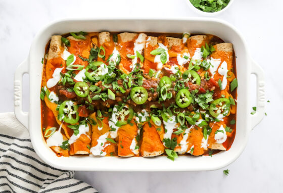 Baked vegan enchiladas topped with green onion and jalapeño slices.