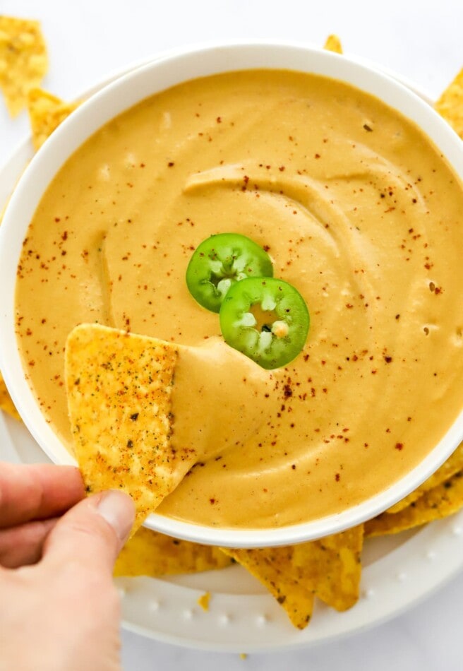 Scooping a chip in vegan queso.