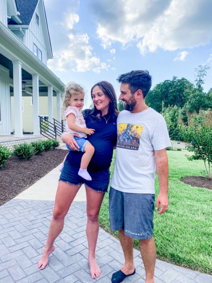 Woman holding a toddler girl with hands around a man.