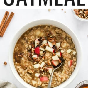 A bowl of apple cinnamon oatmeal topped with extra apple chunks and pecan pieces.