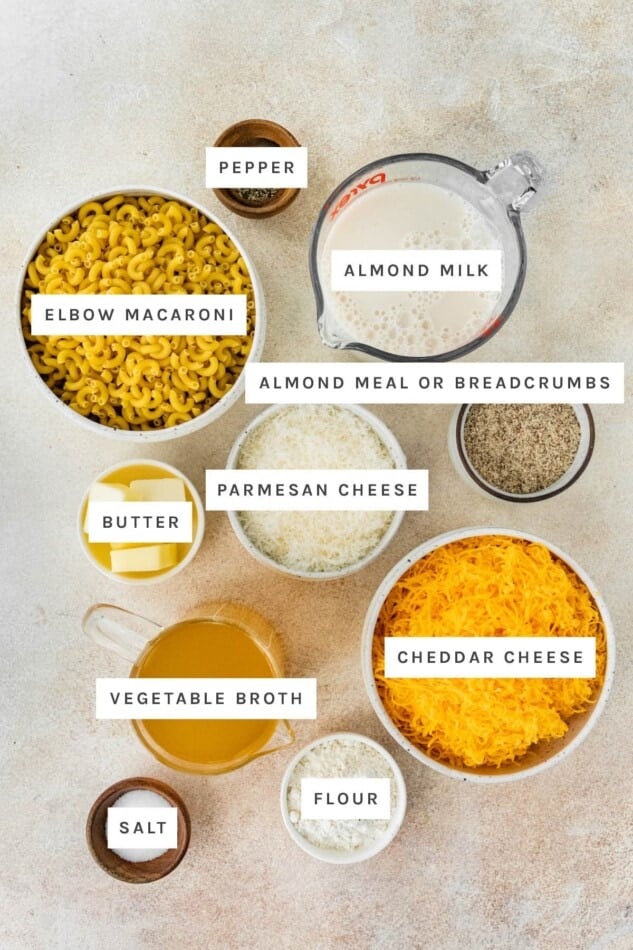 Ingredients measured out to make Healthy Baked Mac and Cheese: pepper, almond milk, almond meal/breadcrumbs, elbow macaroni, parmesan, butter, vegetable broth, cheddar, flour and salt.