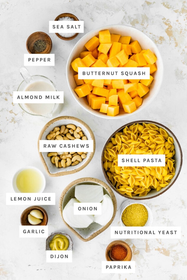 Ingredients measured out to make Butternut Squash Mac and Cheese: sea satl, pepper, butternut squash, almond milk, raw cashews, shell pasta, lemon juice, onion, garlic, nutritional yeast, dijon and paprika.