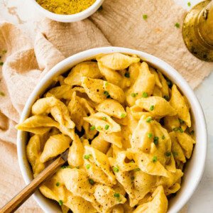 Bowl of vegan butternut squash mac and cheese topped with chives and pepper.