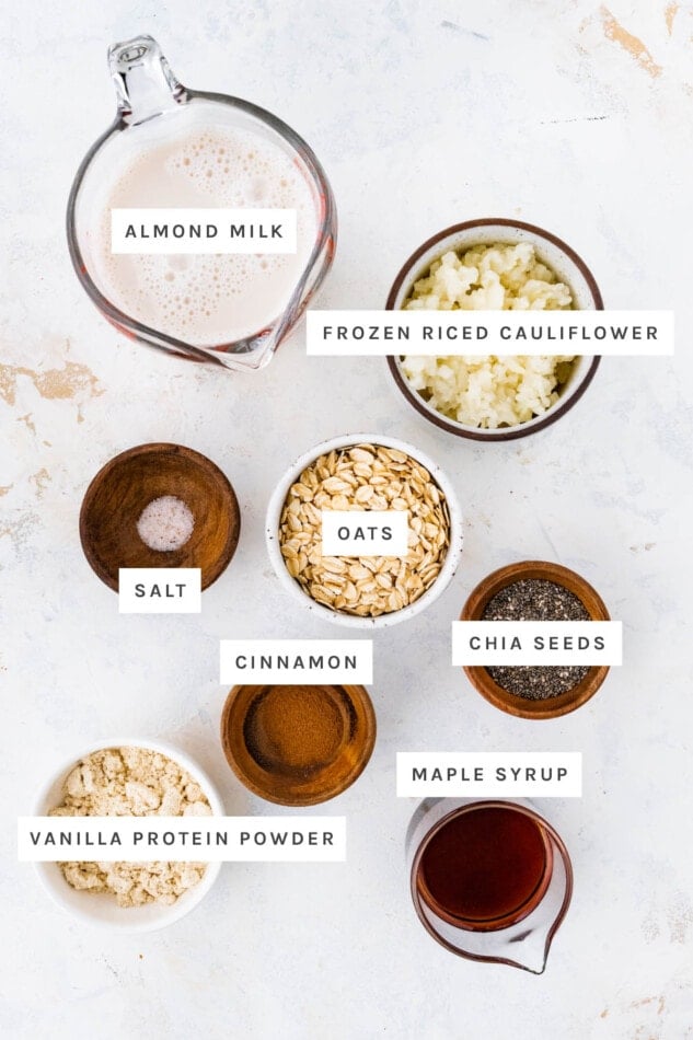 Ingredients measured out to make Cauliflower Oatmeal: almond milk, frozen riced cauliflower, salt, oats, chia seeds, cinnamon, vanilla protein powder and maple syrup.