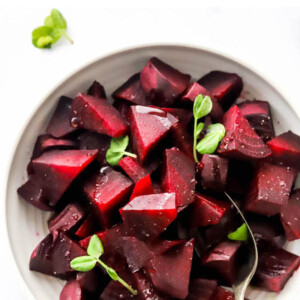 A bowl containing cooked, chopped beets with a serving spoon.