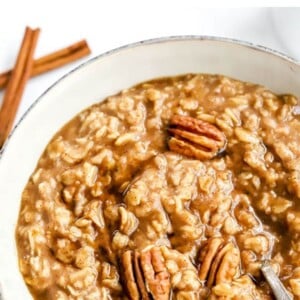 Bowl of maple brown sugar oatmeal topped with pecans. Spoon is in the bowl.
