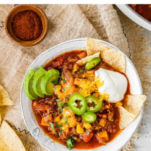 A bowl of no bean chili topped with cheese, jalapeños, avocado, sour cream and chips.