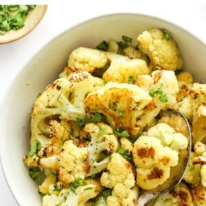 Bowl of roasted cauliflower garnished with fresh parsley.