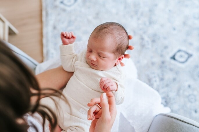 Newborn baby boy holding mom's finger.