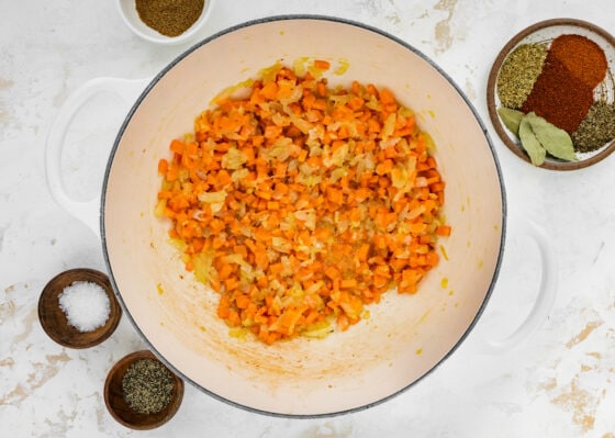 Onions, carrots and garlic sautéing in a pot.