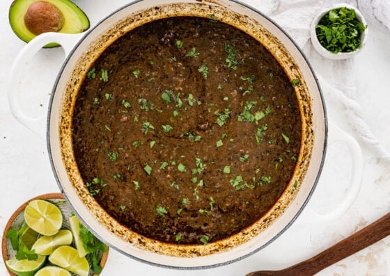 Fresh cilantro added to black bean soup in a pot.