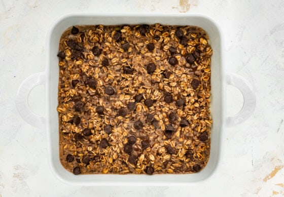 Oatmeal batter in a square baking dish topped with extra chocolate chips.