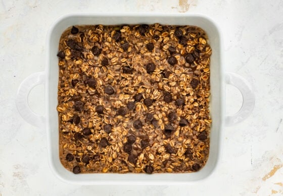 Oatmeal batter in a square baking dish topped with extra chocolate chips.