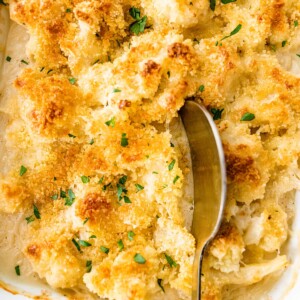 Cauliflower gratin in a baking dish with a serving spoon.