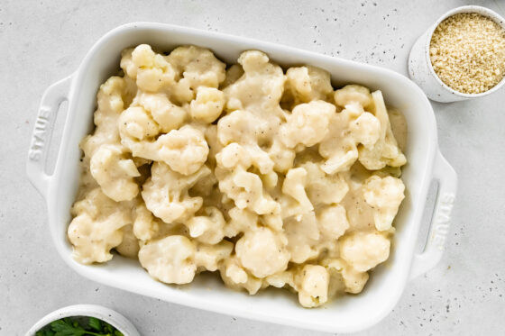 Cheese mixture poured over top of cauliflower florets in a baking dish.