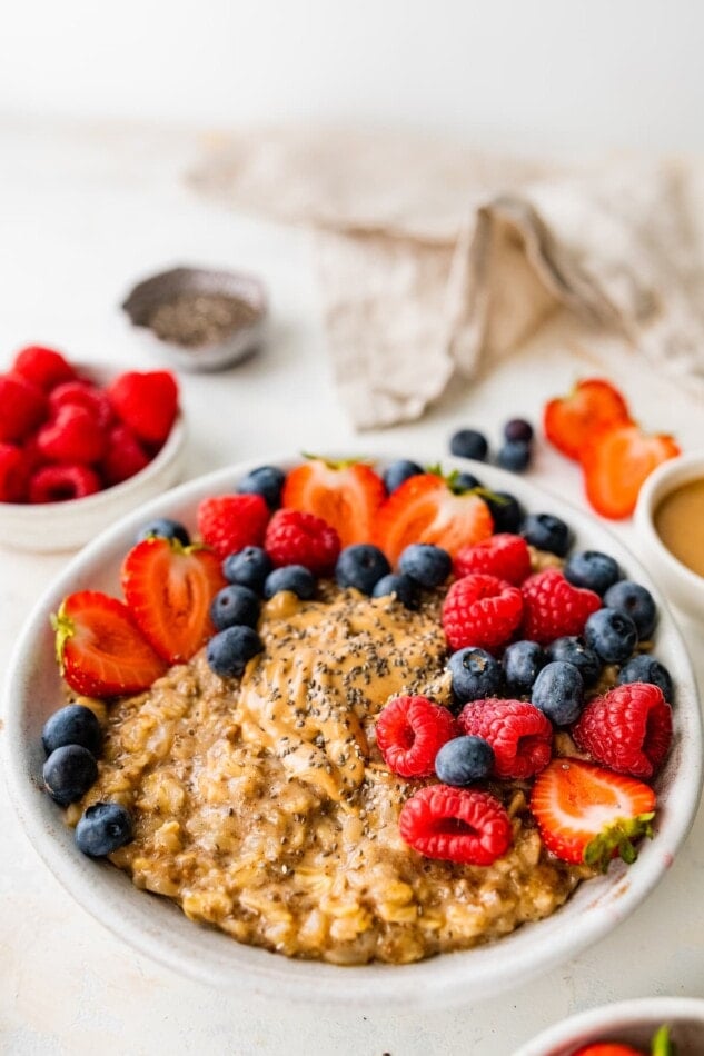 A bowl of cauliflower oatmeal topped with strawberries, raspberries and blueberries.