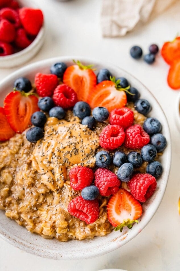 A close up overhead photo of a bowl of cauliflower oatmeal topped with mixed berries.