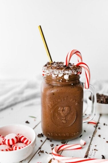 A chocolate peppermint smoothie next to a small candy dish with peppermints.