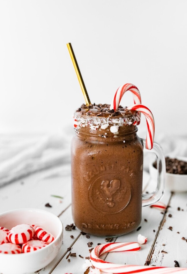 A chocolate peppermint smoothie next to a small candy dish with peppermints.