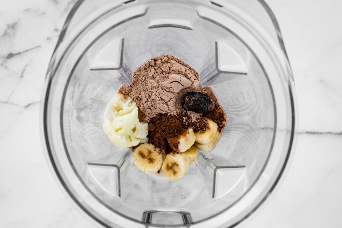Almond milk, frozen banana, cauliflower florets, chocolate protein powder, cocoa powder, medjool date, and peppermint extract in a high powered blender.