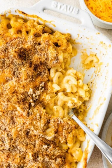 A baking dish containing healthy baked mac and cheese, some portions have been removed.