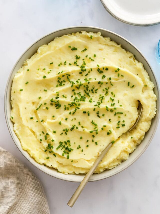 Close up of healthy mashed potatoes in a bowl topped with chives.