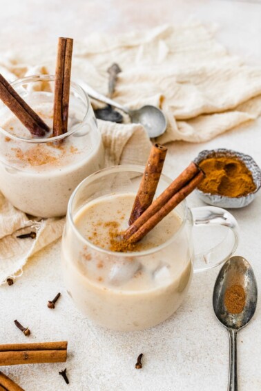 Two glasses of dairy free eggnog with cinnamon sticks.