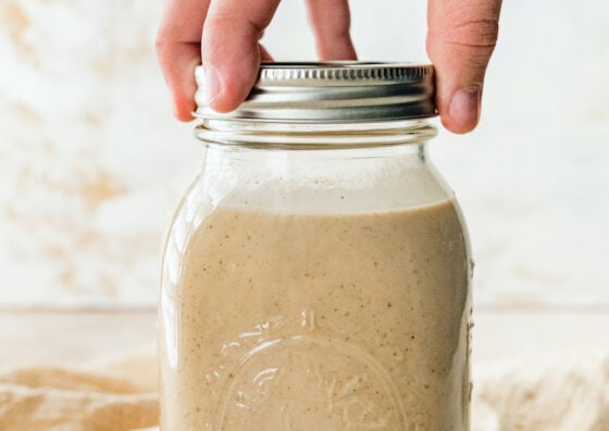 Twisting the lid closed on a mason jar containing dairy free eggnog.