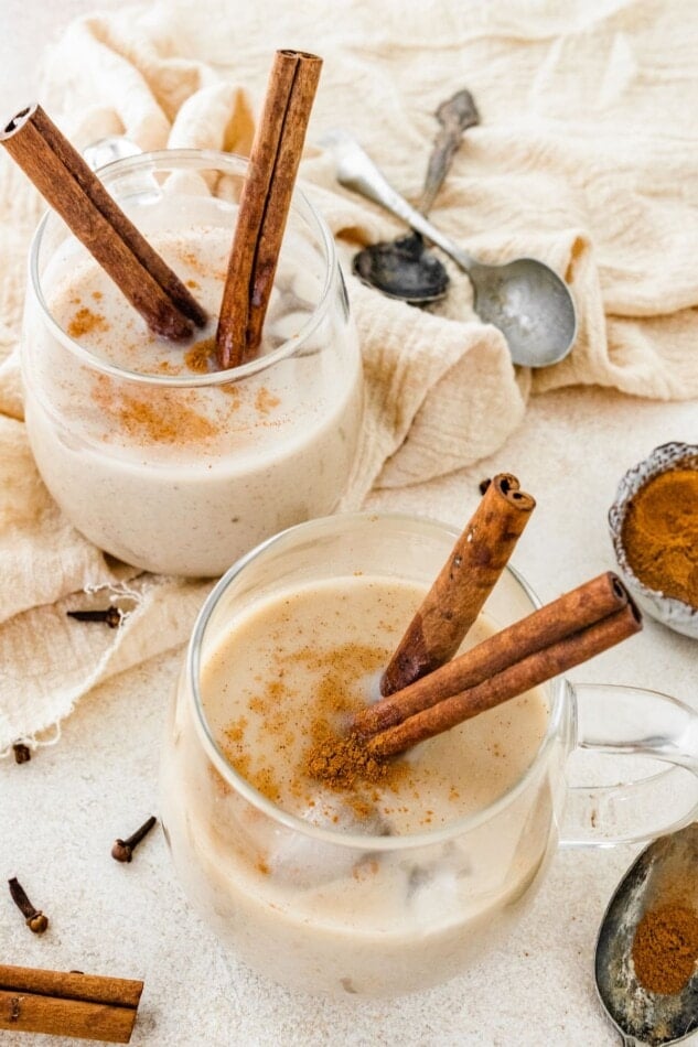 Two glasses of dairy free eggnog with cinnamon sticks.