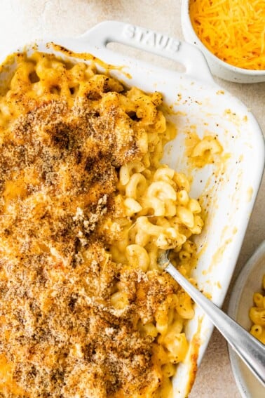 A baking dish containing healthy baked mac and cheese, some portions have been removed.