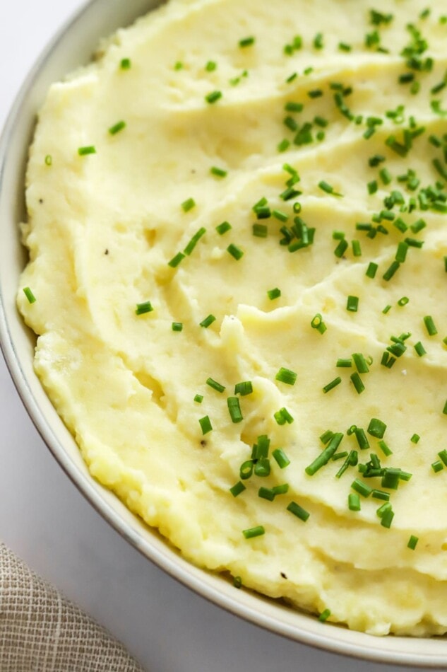 Close up of healthy mashed potatoes in a bowl topped with chives.