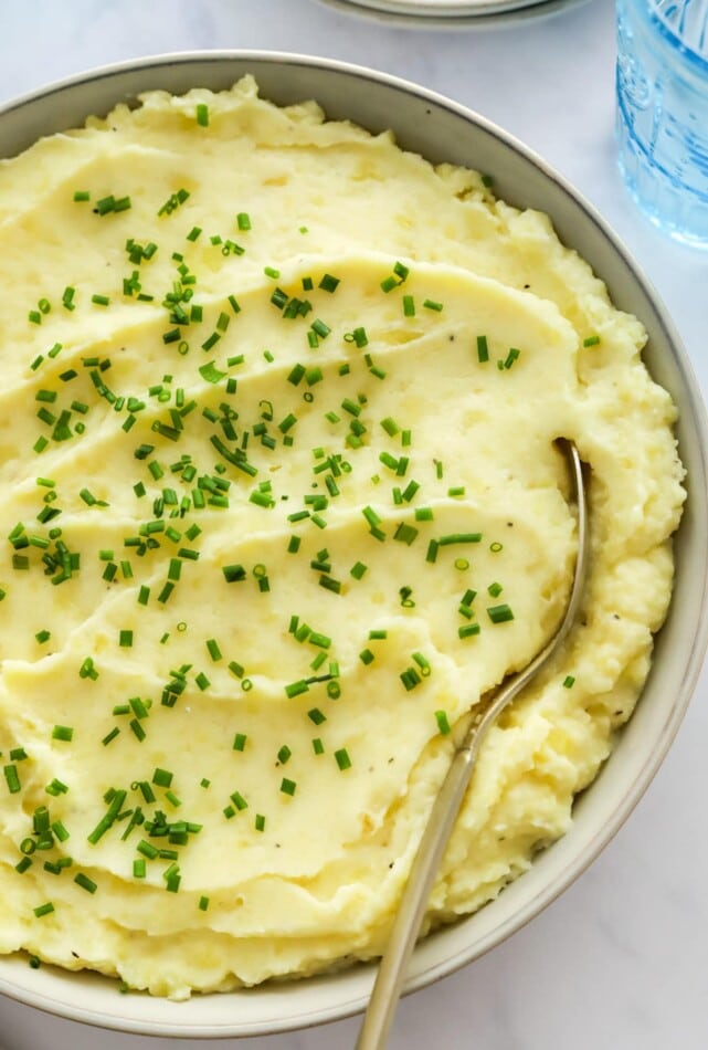 Close up of healthy mashed potatoes in a bowl topped with chives.