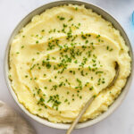 Close up of healthy mashed potatoes in a bowl topped with chives.