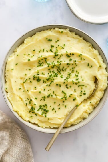 Close up of healthy mashed potatoes in a bowl topped with chives.