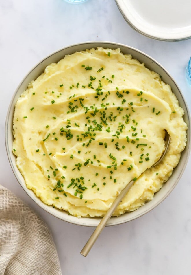 Close up of healthy mashed potatoes in a bowl topped with chives.