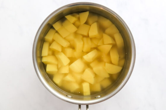 Potato pieces in a pot covered with water.