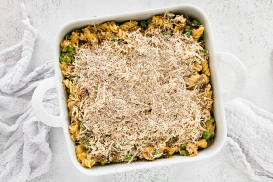 Pasta mixture in the prepped 8x8 baking dish topped with parmesan cheese and breadcrumbs.