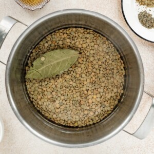 Lentils and a bay leaf in a pot covered with water.